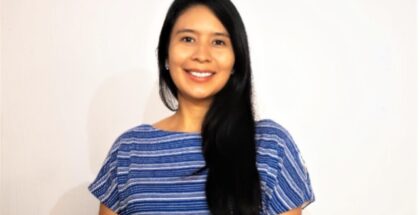 Picture of Alejandra Rivera, a woman wearing a blue striped top with black hair falling over her left shoulder