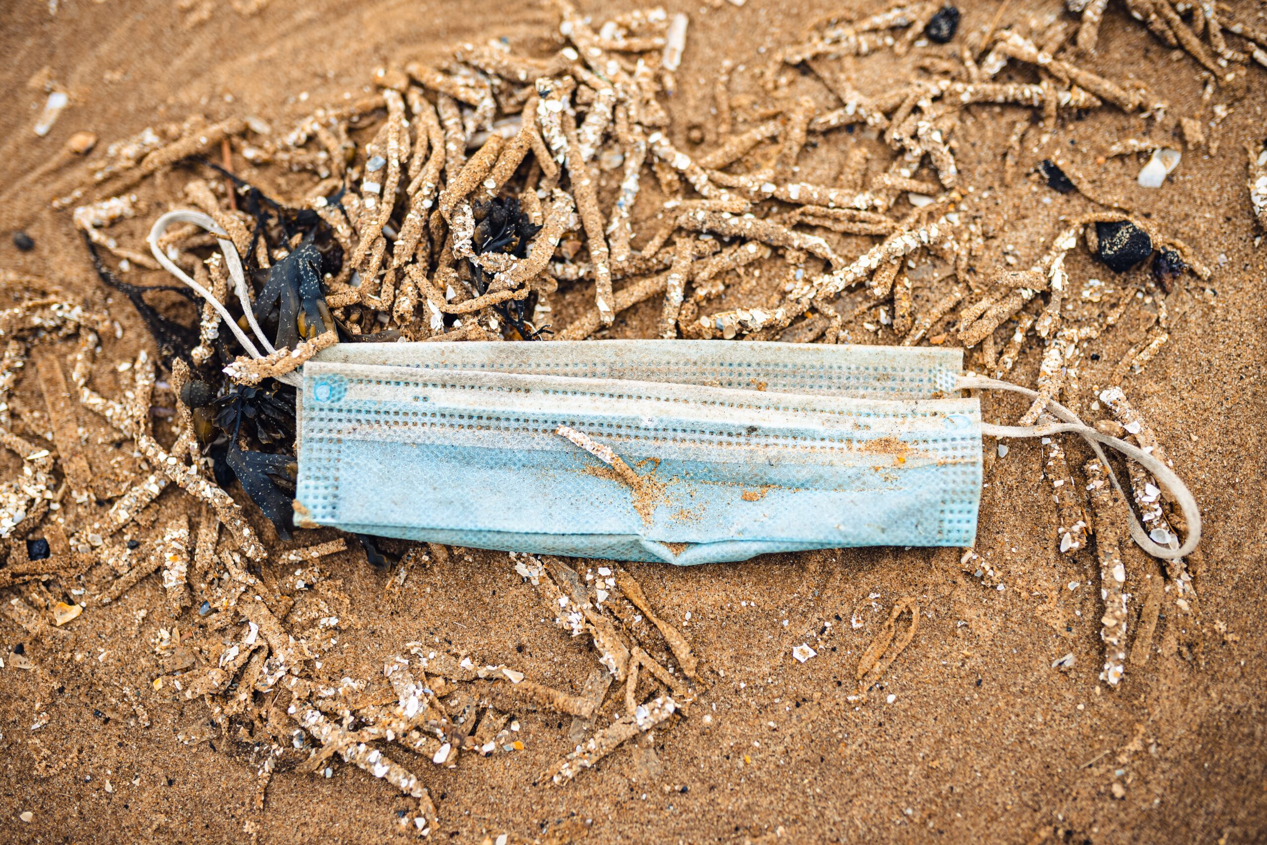 Image shows a soiled disposable mask lying on ground