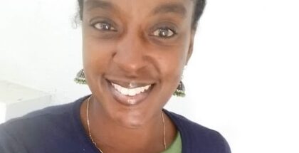 Image shows the face of a woman in a blue sweater smiling at the camera