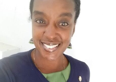 Image shows the face of a woman in a blue sweater smiling at the camera